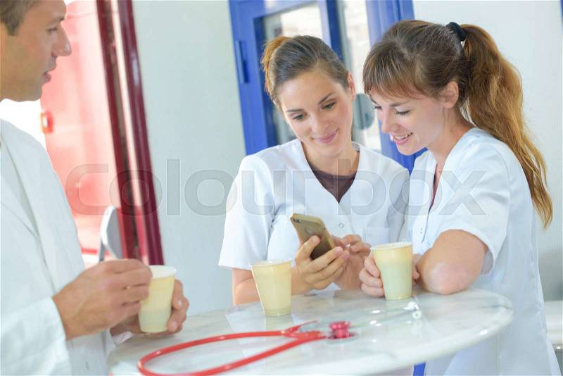 Nurses on tea break looking at smartphone, stock photo