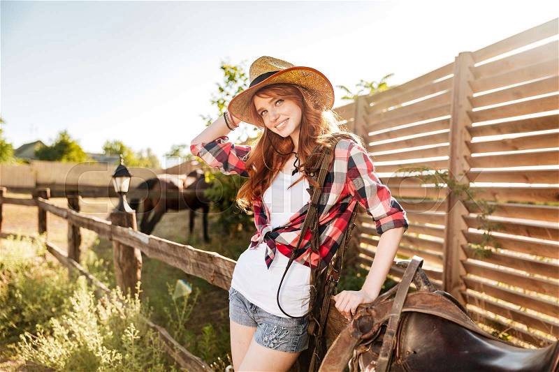 Portrait of happy beautiful young woman cowgirl in hat on ranch, stock photo