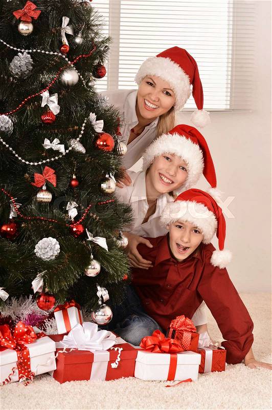 Cute mom and her kids in santa hats with gifts, stock photo