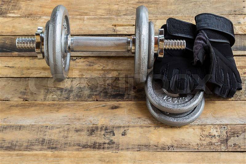 Top view of dumbbells, extra weights and black gloves on the wooden floor.Sport lifestyle and fitness concept, stock photo