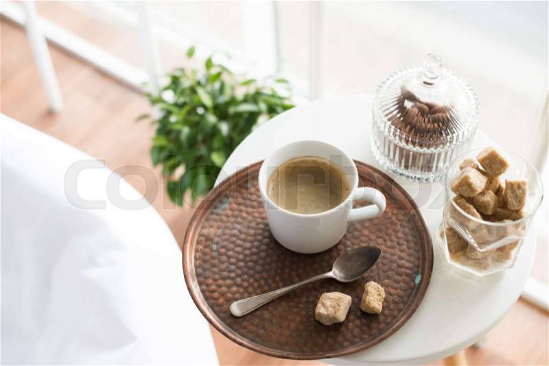 Coffee with sweets served on table in cozy loft room interior with large windows, closeup, stock photo