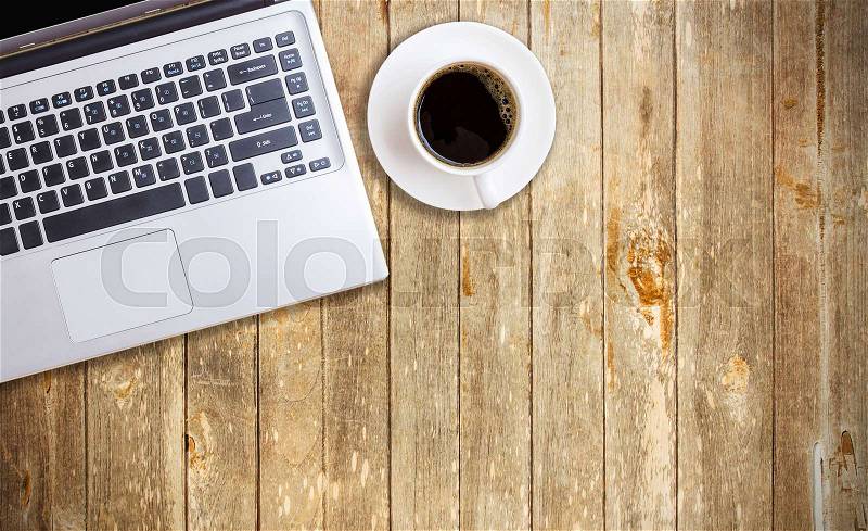 Vintage wood working table with laptop and cup of coffee. Top view with copy space, stock photo