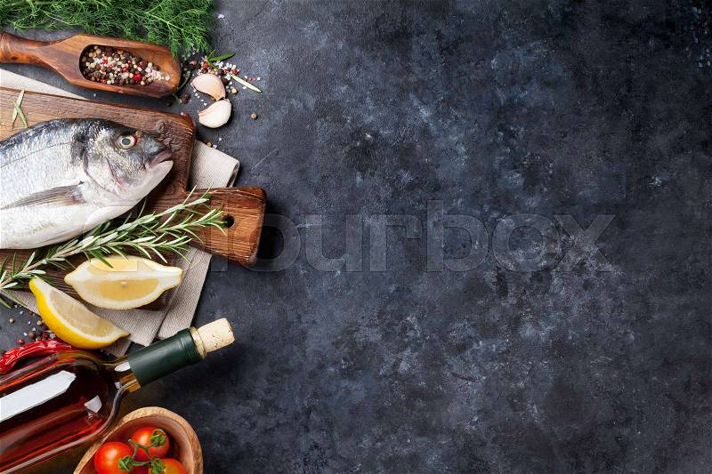 Raw fish cooking and ingredients. White wine, dorado, lemon, herbs and spices. Top view with copy space on stone table, stock photo