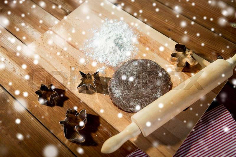 Baking, cooking, christmas and food concept - close up of gingerbread dough, metal molds and rolling pin with flower on wooden cutting board at home kitchen from top, stock photo