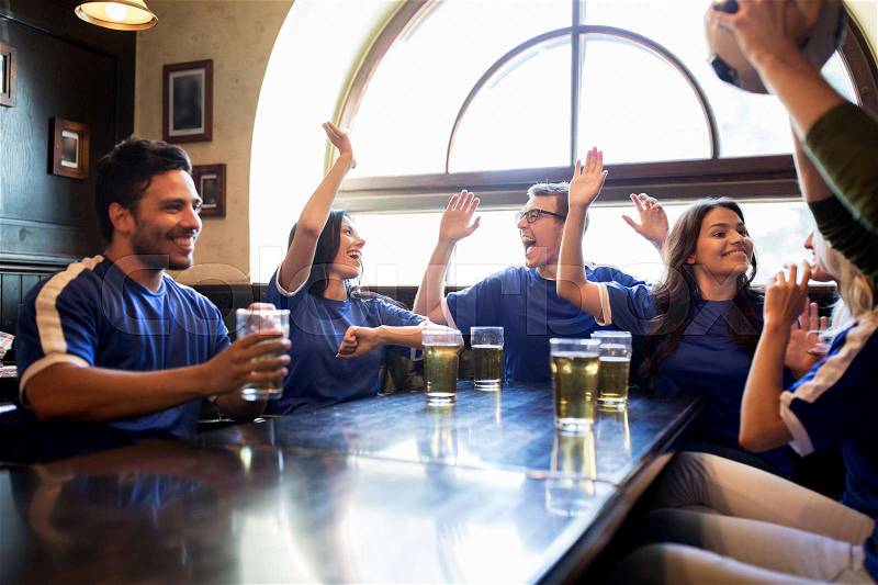 Sport, people, friendship and entertainment concept - happy football fans or friends drinking beer, making high five and celebrating victory at bar or pub, stock photo