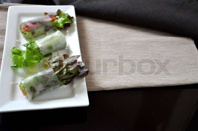 Veggie rolls on plate with copy space on light brown fabric background, stock photo