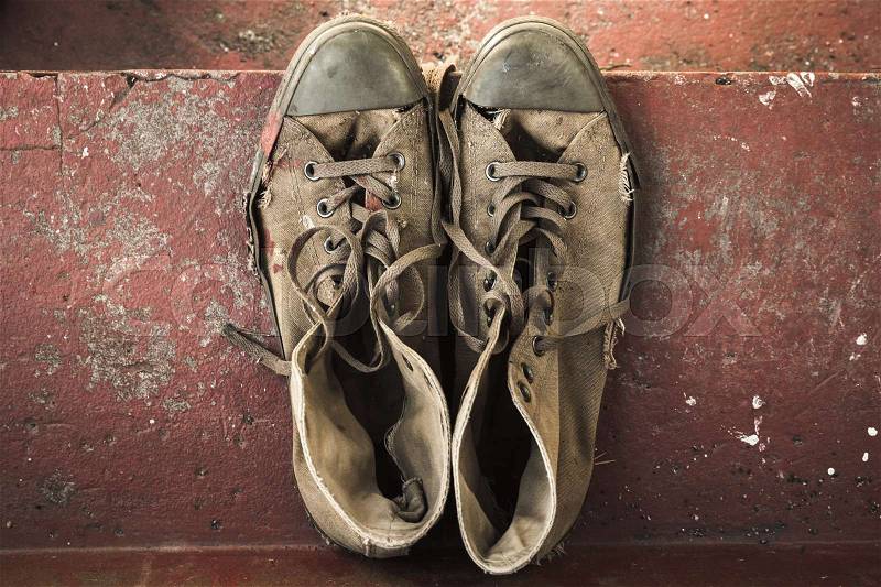 Old sneakers stand on red concrete stairs, top view, stock photo