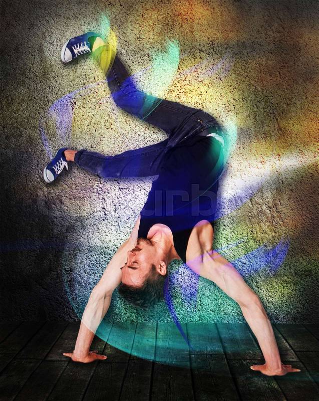 The break dancer doing handstand against colorful wall background, stock photo