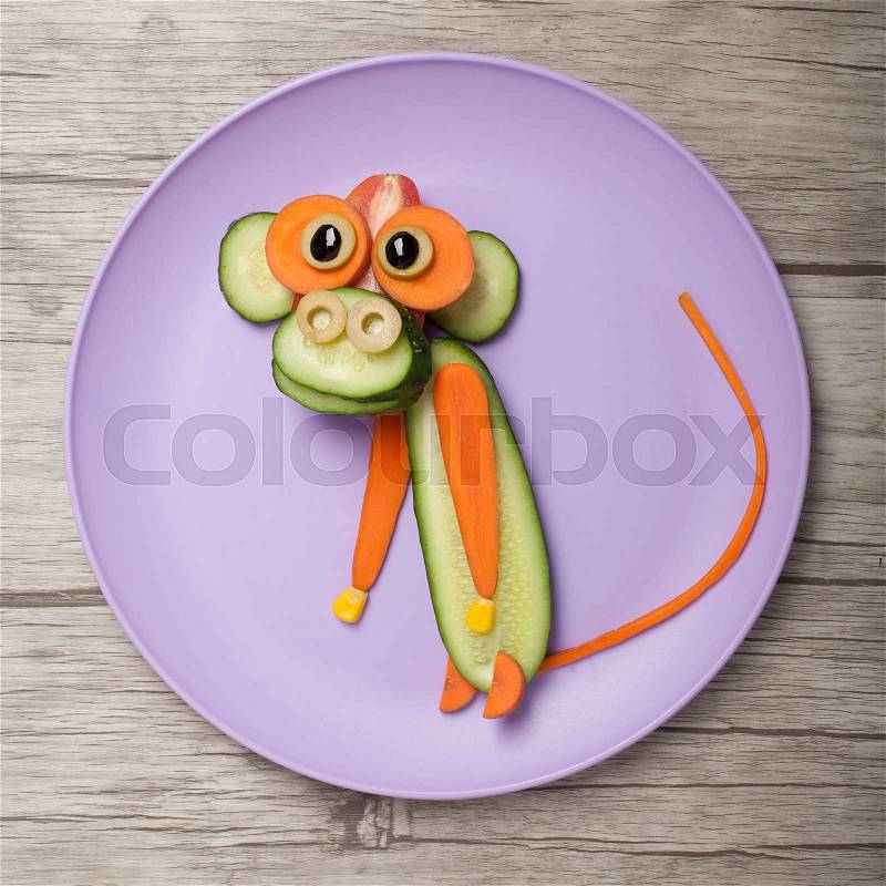 Monkey made of cucumber and carrot on board and plate, stock photo