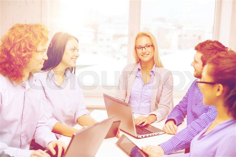 Business, office and startup concept - smiling creative team with table pc and laptop computers working in office, stock photo