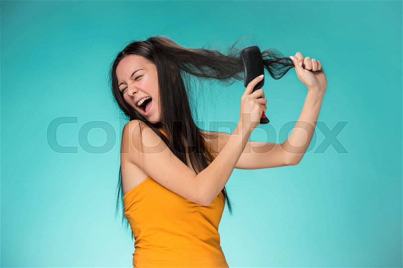 Frustrated young woman having a bad hair on blue, stock photo