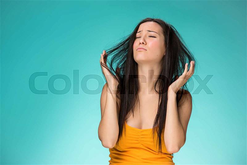 Frustrated young woman having a bad hair on blue, stock photo