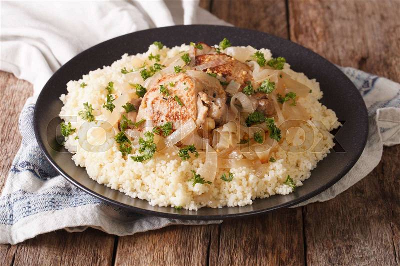 Tasty African food: Chicken Yassa with marinated onions and couscous close up on a plate. horizontal , stock photo