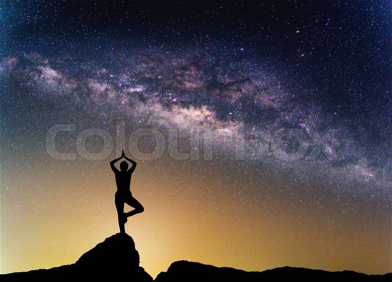 Landscape with Milky way galaxy. Night sky with stars and silhouette woman practicing yoga on the mountain, stock photo