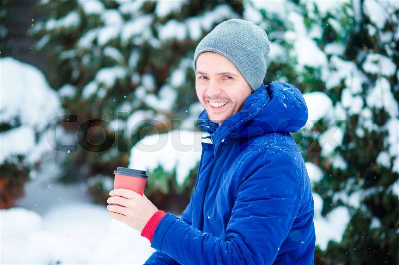 Young caucasian man drinking hot coffee in frozen winter day outdoors, stock photo