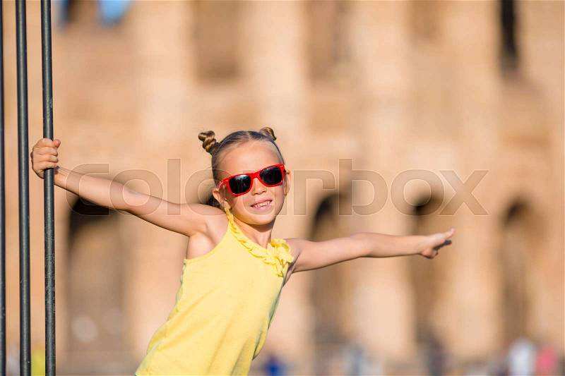 Adorable little active girl having fun in front of Colosseum in Rome, Italy. Kid spending childhood in Europe, stock photo