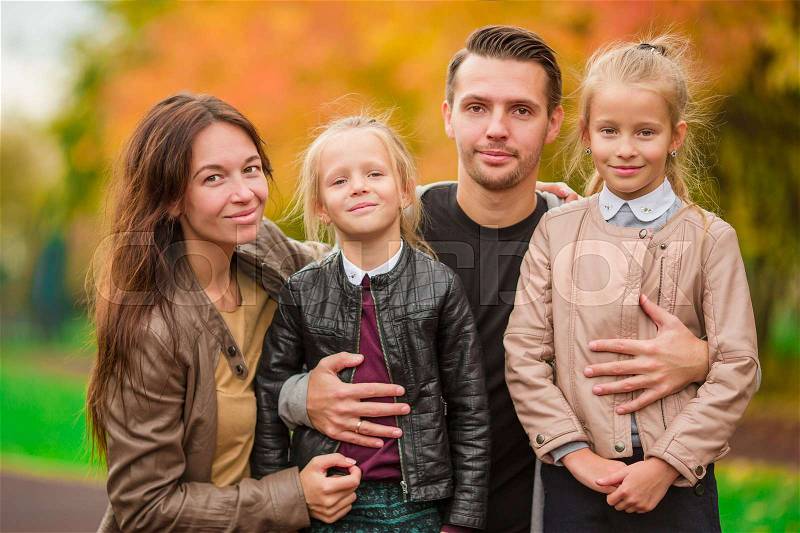 Young family with cute little girls in autumn park on sunny day, stock photo