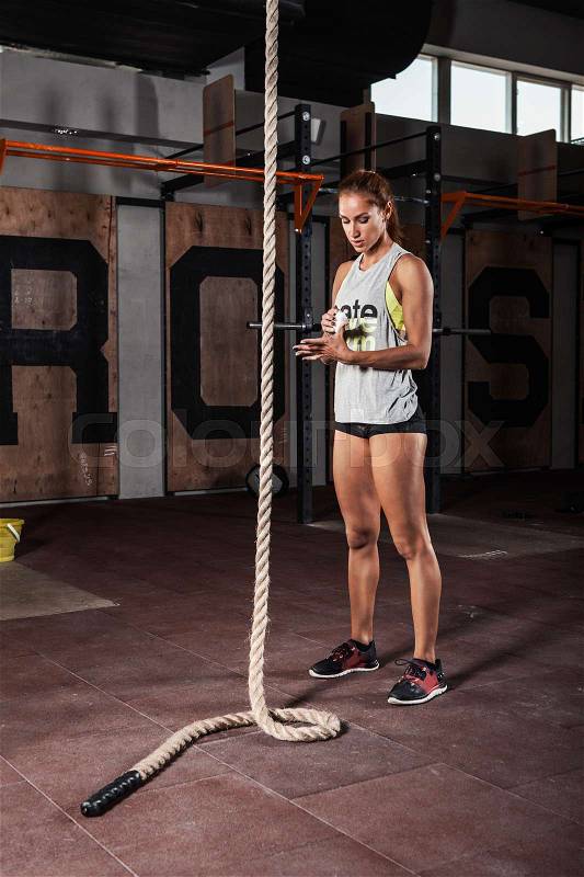 Young woman preparing for the rope climb exercise in gym, stock photo