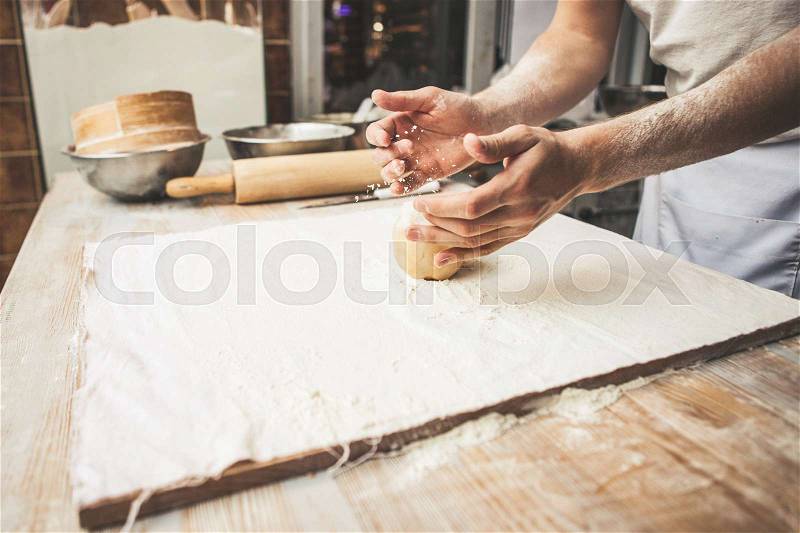 Making dough by male hands at bakery, stock photo