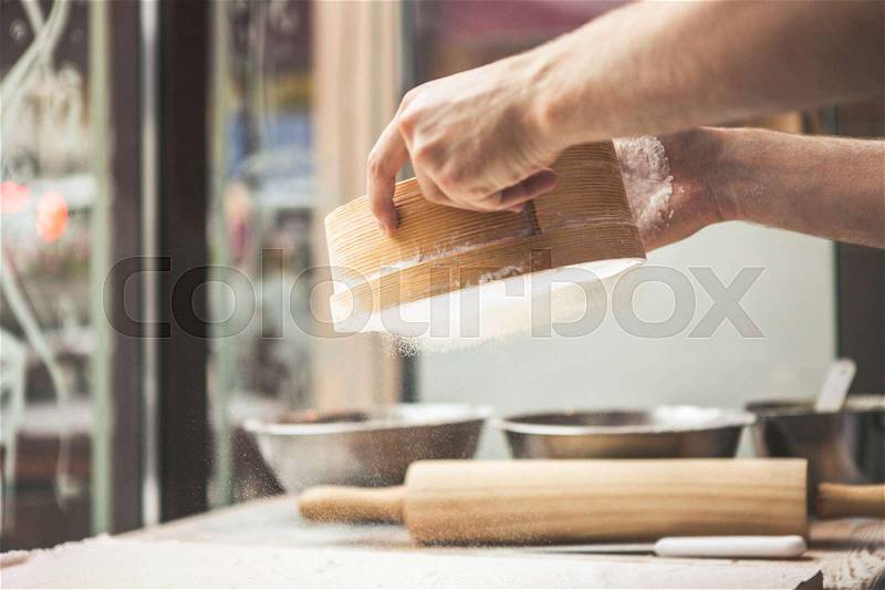 Man preparing dough. Ingredients for baking. Man hands spilling powder on dough. Cooking and baking concept, stock photo