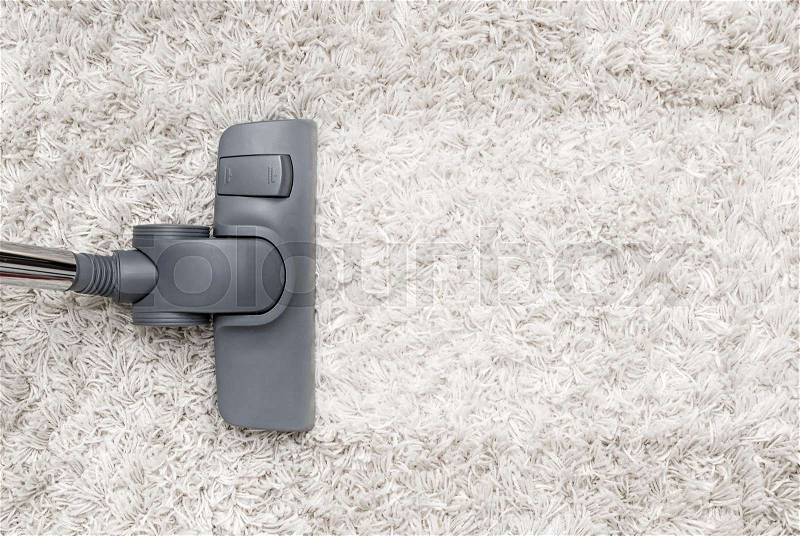Vacuum cleaner cleans the white shaggy carpet. View from top, stock photo