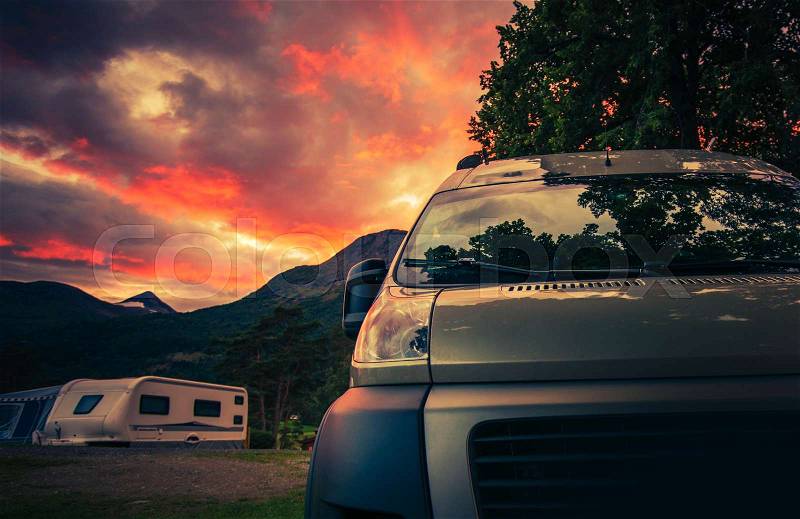 Scenic RV Park Camping During Beautiful Summer Sunset. Motorhome and Travel Trailers in the Background, stock photo