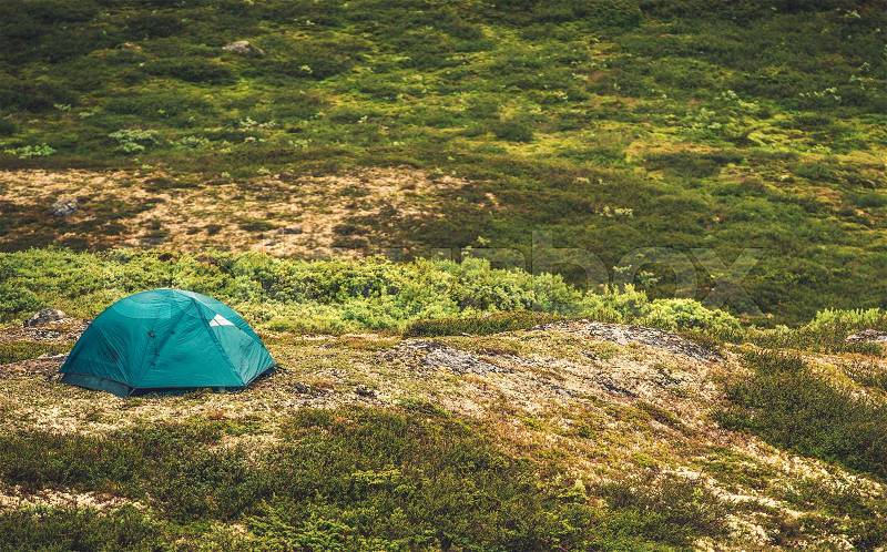 Tent Camping in the Wild. Small Tent on the Remote Mountain Landscape Meadow, stock photo