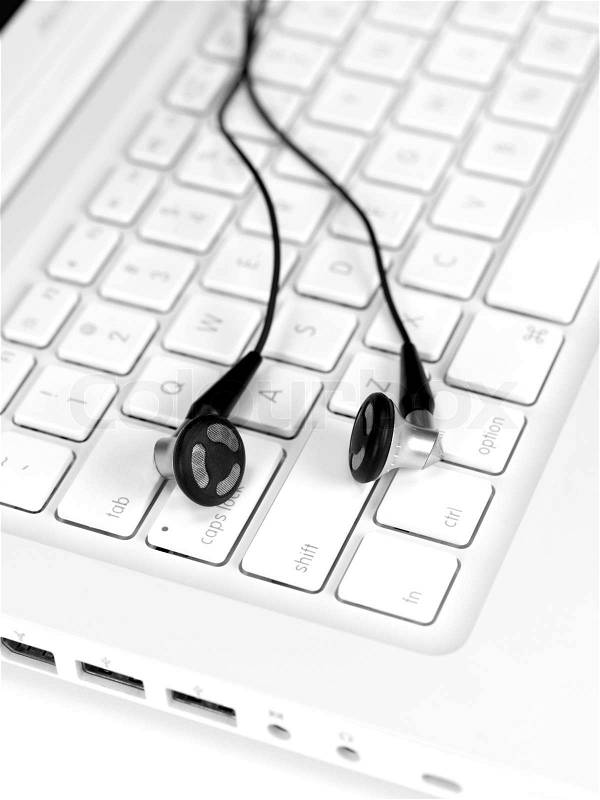 A laptop computer with a set of earphones isolaterd against a white background, stock photo