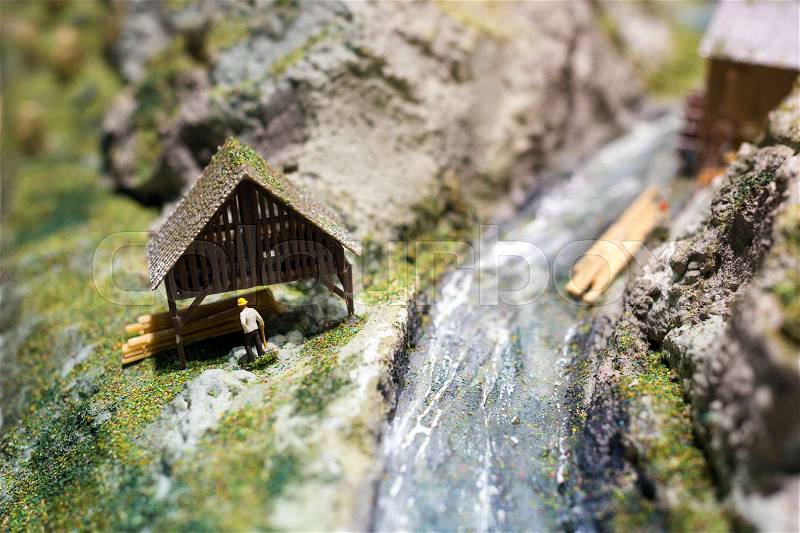 Miniature people: worker on sawmill at the river. Macro photo, shallow DOF, stock photo