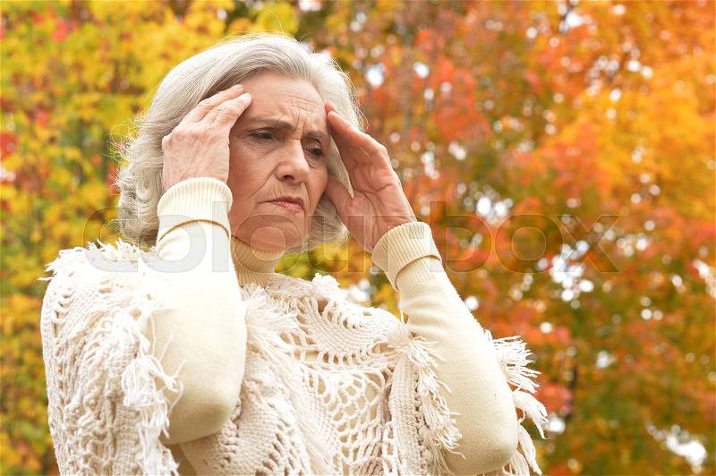 Portrait of a sad elderly woman in autumn park, stock photo