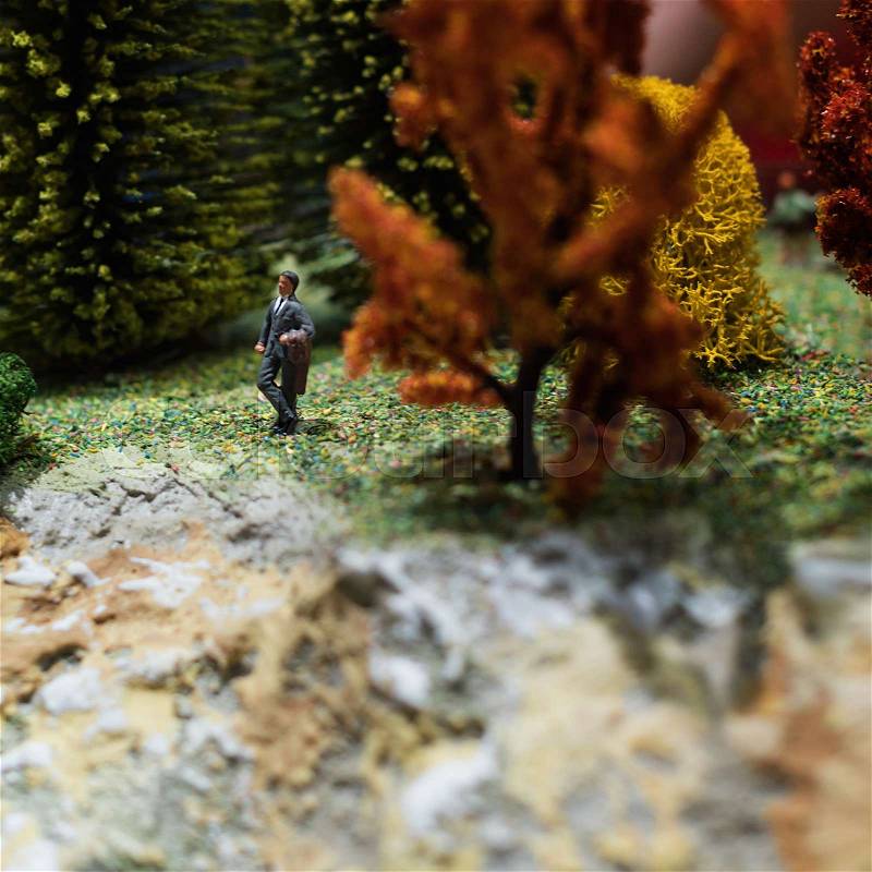 Miniature people: relaxed businessman standing in the forest. Working outdoor green nature concept. Macro photo, shallow DOF, stock photo