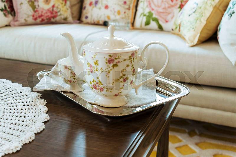 Ceramic teapot and cups on a stainless steel tray in living room, stock photo