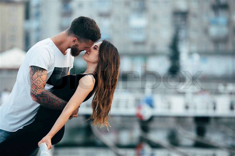 Couple kissing against the backdrop of the city by the lake, stock photo