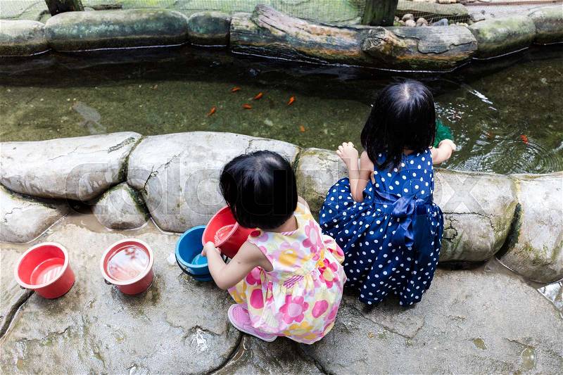 Asian Chinese Little Girls Fishing With Scoop Net At Outdoor Man-made Pond, stock photo