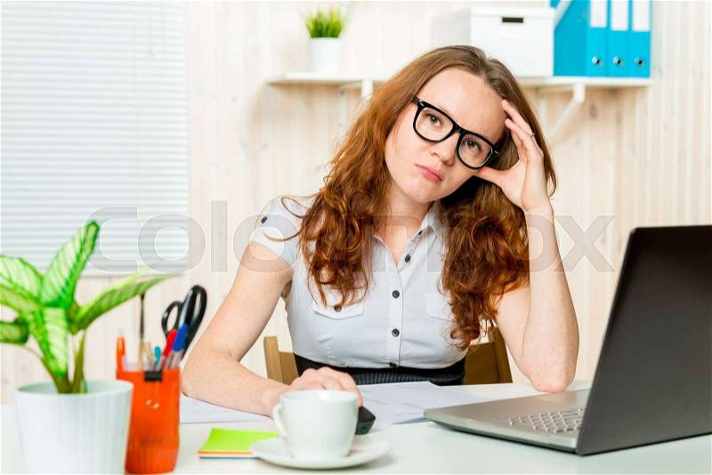 Portrait of a tired office worker at a computer at the end of the working day, stock photo
