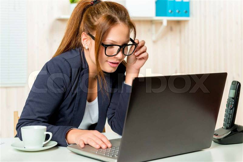 Beautiful secretary carefully scans email on the computer in the office environment, stock photo