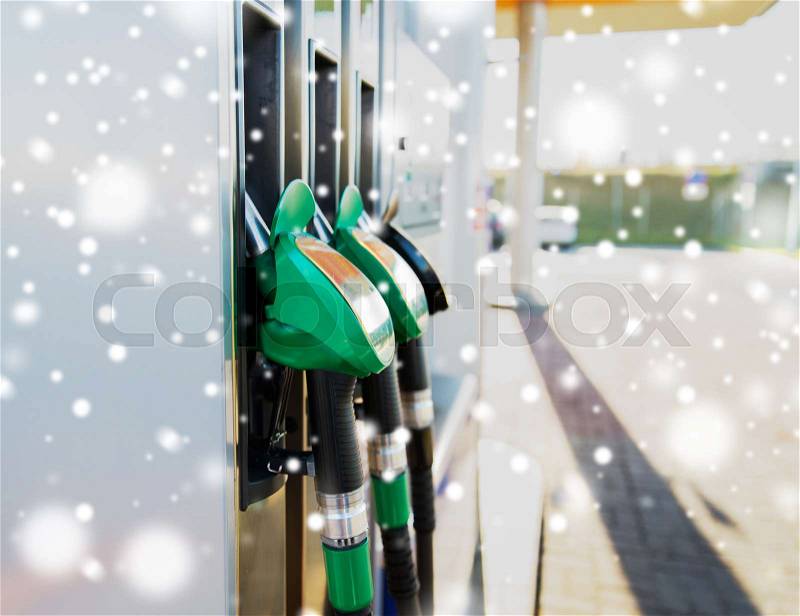 Winter, fuel, oil, tank and transport concept - close up of gasoline hose at gas station over snow, stock photo