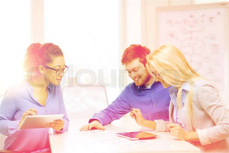 Business, office and startup concep - smiling creative team with table pc computers and papers working in office, stock photo
