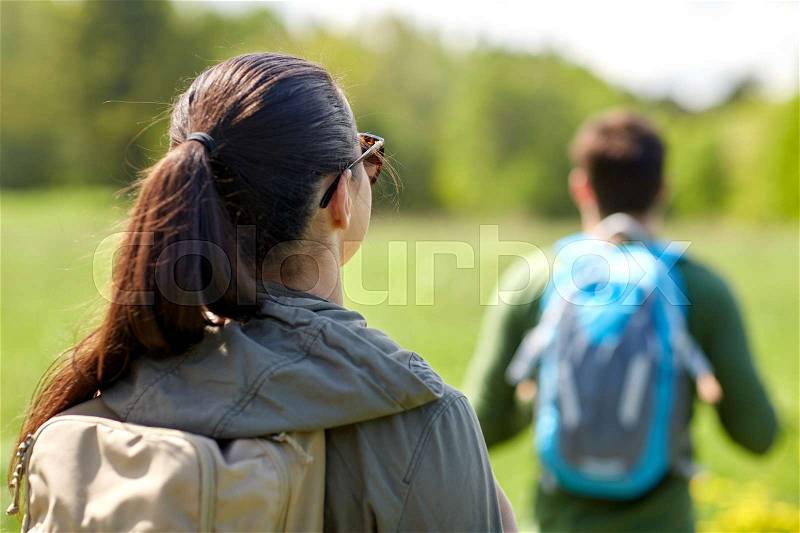 Travel, hiking, backpacking, tourism and people concept - close up of couple with backpacks walking along country road, stock photo