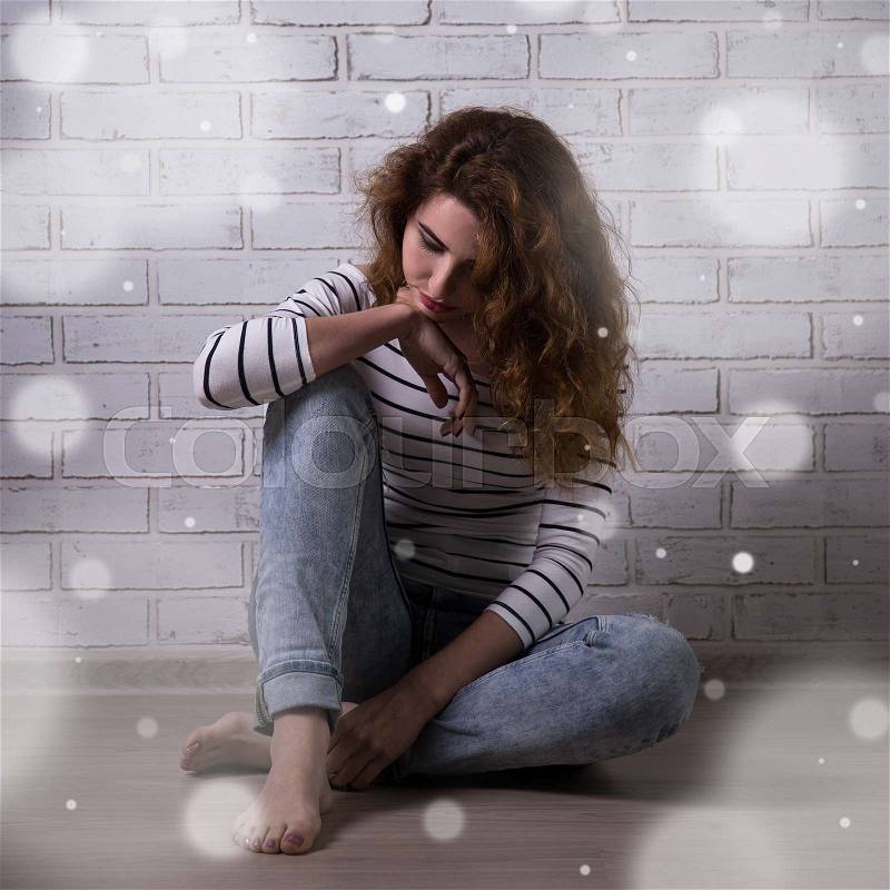 Winter depression - young unhappy woman sitting on the floor, stock photo