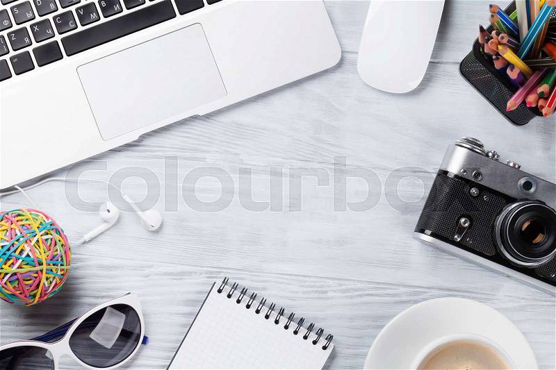 Desk table with laptop, coffee cup, headphones and camera on wooden table. Workplace. Top view with copy space, stock photo