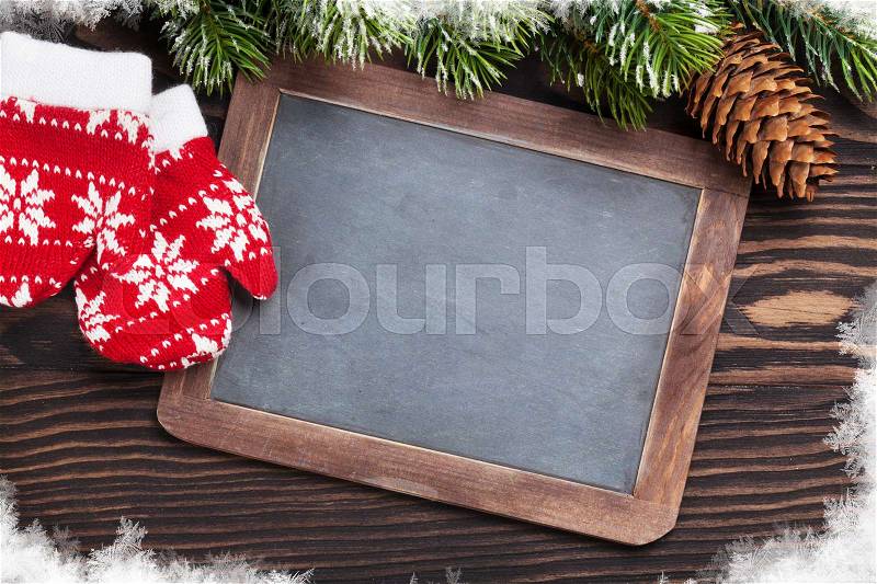 Christmas chalkboard, mittens and fir tree on wooden table. Top view with copy space for your text, stock photo