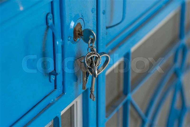 Key in hold key on blue steel door, stock photo