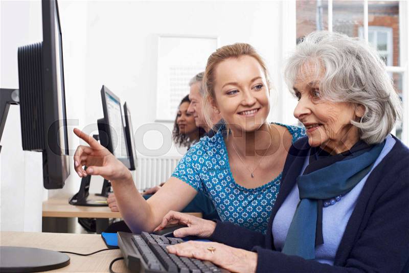 Tutor Helping Senior Woman In Computer Class, stock photo