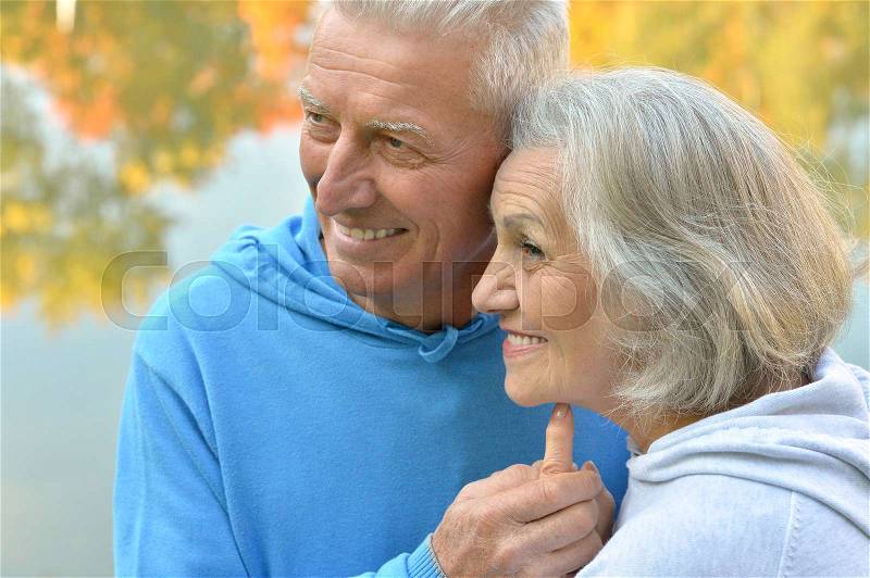 Happy senior couple near river at autumn ,blurred background, stock photo