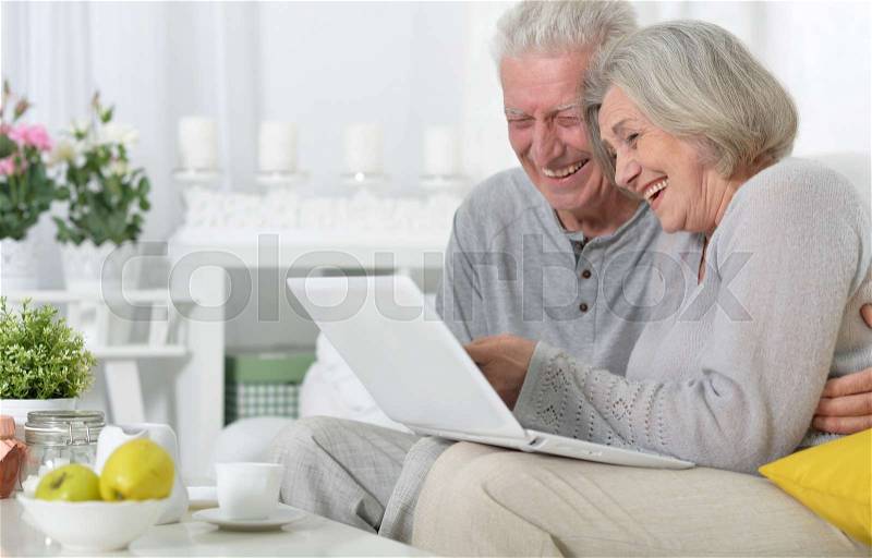 Senior couple portrait with laptop at home, stock photo