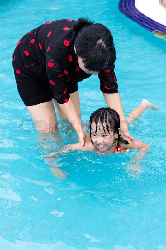 Asian Chinese Mom Teaching Little Girl Swimming At The Outdoor Pool, stock photo