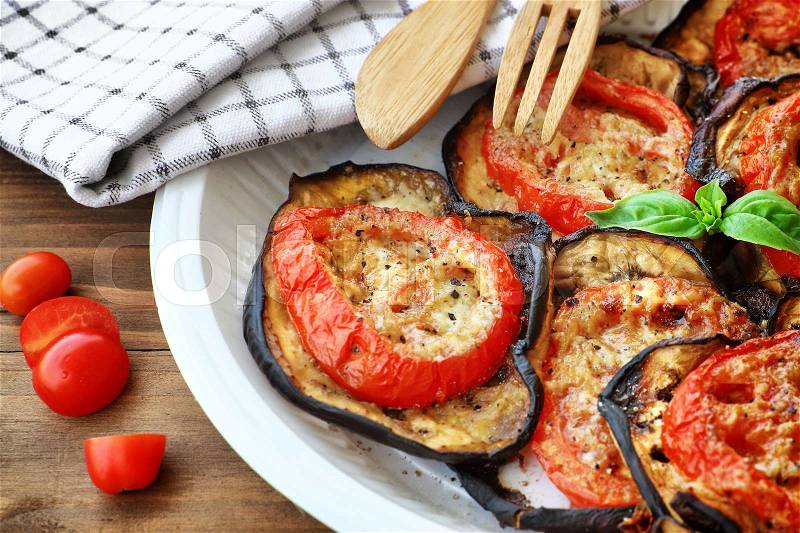 Tasty Thanksgiving meal, roasted aubergine with tomatoes and cheese on the plate on wooden table, delicious homemade food, stock photo