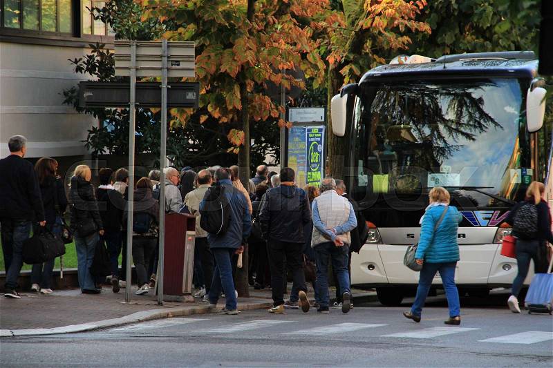The passengers, tourists, going into the bus in one of the streets in the city Montecatini in Italy at sunrise in autumn, stock photo