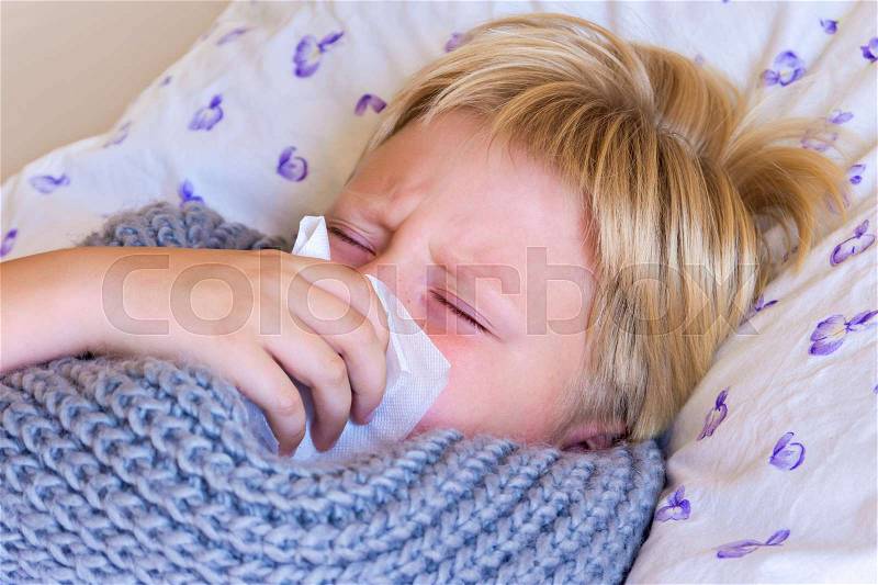 Sick little child boy blowing nose laying in bed with sad face - healthcare and medicine concept, stock photo